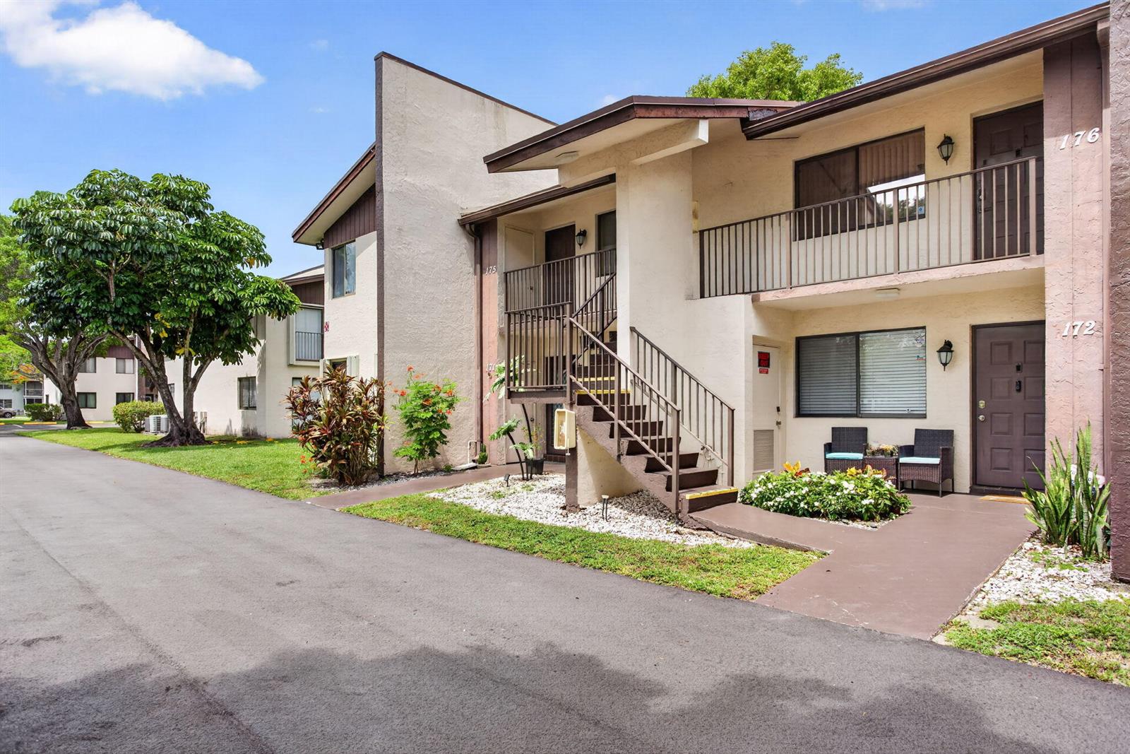 A two-story apartment building exterior features a staircase, balconies, and a paved walkway — 172 W Laurel Drive # 1102, Margate FL 33063, MARGATE, FL