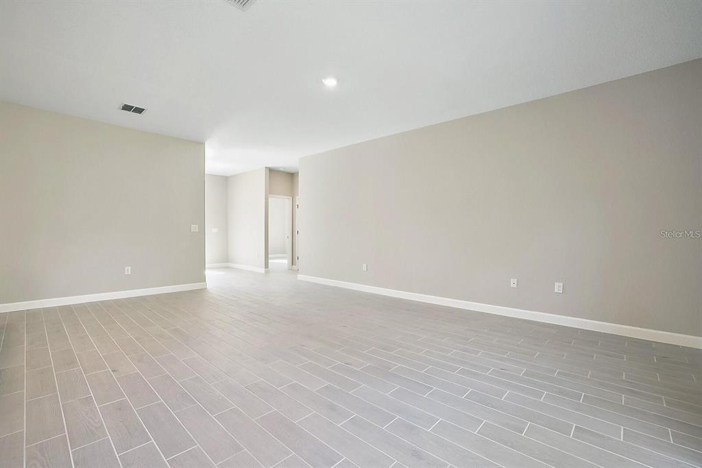 An empty room features light gray wood-look tile flooring and neutral painted walls — 1011 KISMET PARKWAY W, CAPE CORAL, FL