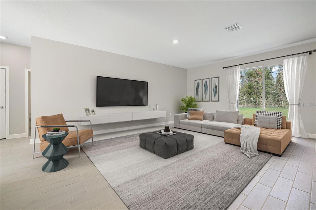 A modern living room features a wall-mounted television, a sectional sofa, and a large rug — 1011 KISMET PARKWAY W, CAPE CORAL, FL
