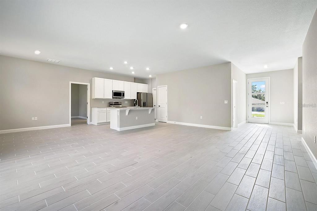 An open-concept kitchen and living area features light gray tile flooring and white cabinetry — 1011 KISMET PARKWAY W, CAPE CORAL, FL