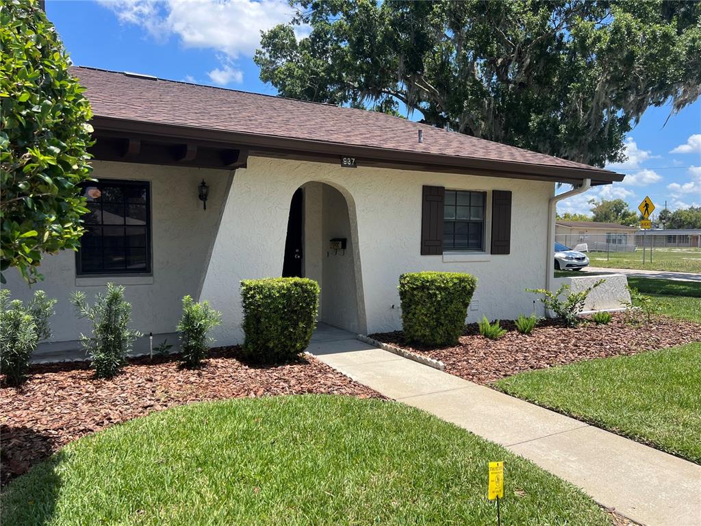 A single-story house with a stucco exterior, brown roof, and a recessed arched entryway — 937 MICHIGAN AVENUE, ST CLOUD, FL