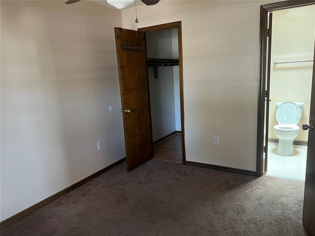 A bedroom with brown carpet, a walk-in closet, and an attached bathroom with a toilet — 937 MICHIGAN AVENUE, ST CLOUD, FL