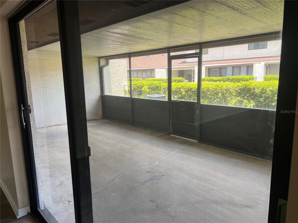 A concrete-floored screened-in porch is viewed through a sliding glass door — 937 MICHIGAN AVENUE, ST CLOUD, FL