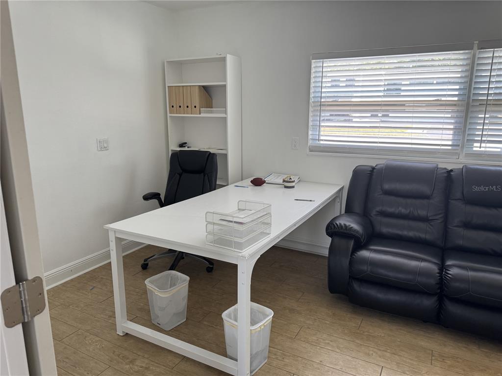 A home office features a white desk, black office chair, black sofa, and wood-look flooring — 501 S LINCOLN AVENUE UNIT 20, CLEARWATER, FL