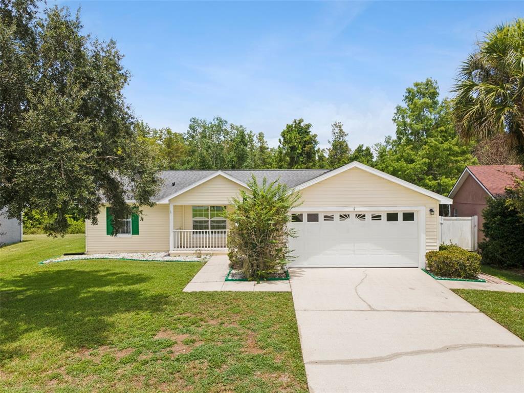A single-story house with light yellow siding, a two-car garage, and a front porch — 3829 SPRINGLAKE VILLAGE COURT, KISSIMMEE, FL