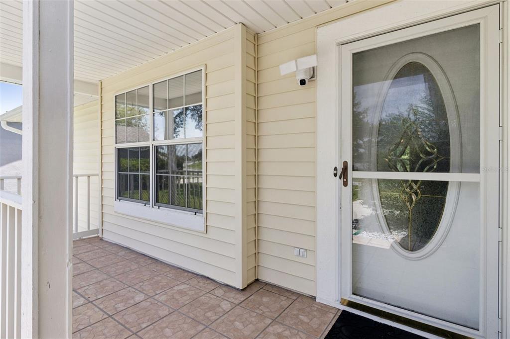 A covered porch features light yellow siding, a tiled floor, and a white storm door — 3829 SPRINGLAKE VILLAGE COURT, KISSIMMEE, FL