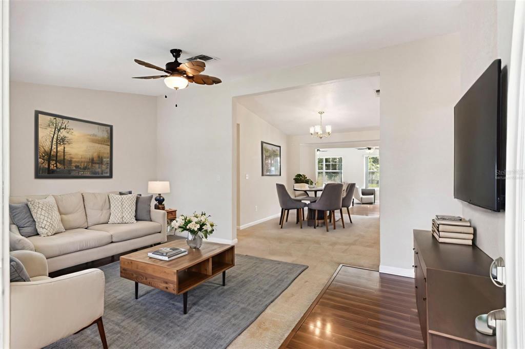 A living room with a beige sofa, wood coffee table, and an adjacent dining area — 3829 SPRINGLAKE VILLAGE COURT, KISSIMMEE, FL