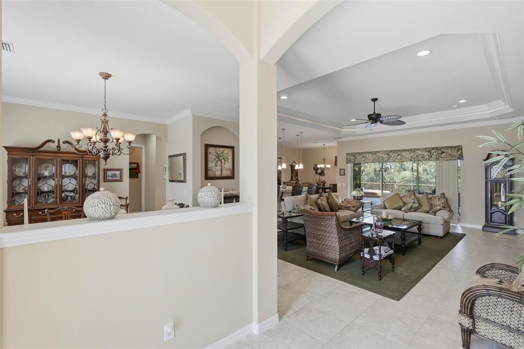 A view from a hallway into a living room with a tray ceiling and chandelier — 12619 50TH COURT E, PARRISH, FL