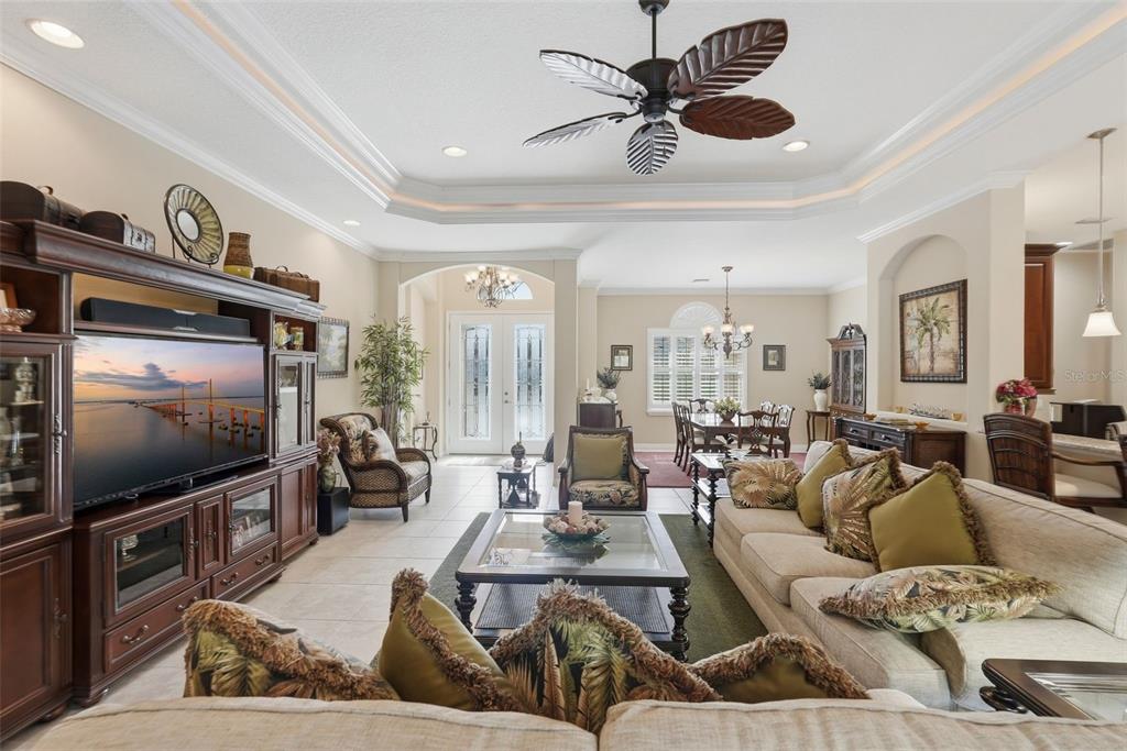 A spacious living room features a large entertainment center, a tray ceiling, and tile flooring — 12619 50TH COURT E, PARRISH, FL