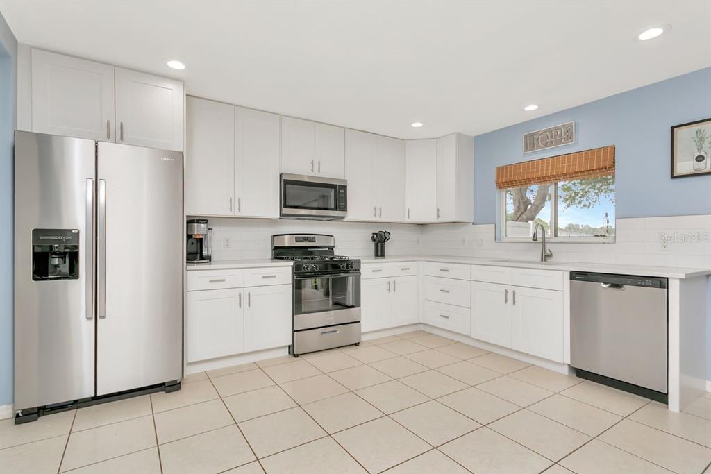 A kitchen with white cabinets, stainless steel appliances, and light-colored tile flooring — 6818 WATERTON DRIVE, RIVERVIEW, FL