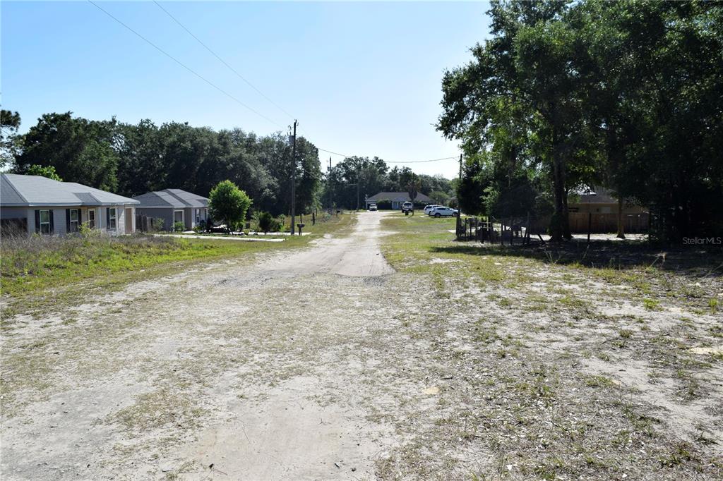 A dirt road runs through a residential neighborhood with houses and trees on both sides — TBD SW 34 STREET, OCALA, FL