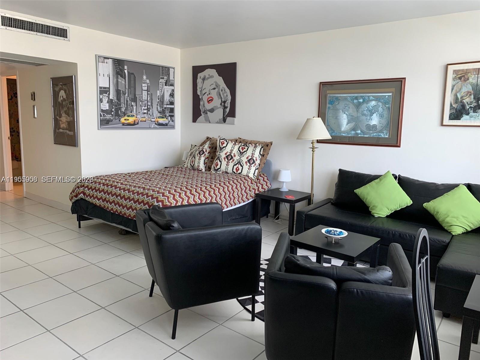 A studio apartment features a bed, black leather seating, and framed wall art — 100 Lincoln Rd # 903, Miami Beach FL 33139, MIAMI BEACH, FL