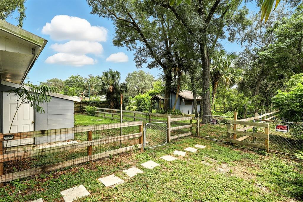 A fenced backyard features a small shed, a grassy lawn, and a stone pathway — 1412 E VOORHIS AVENUE, DELAND, FL