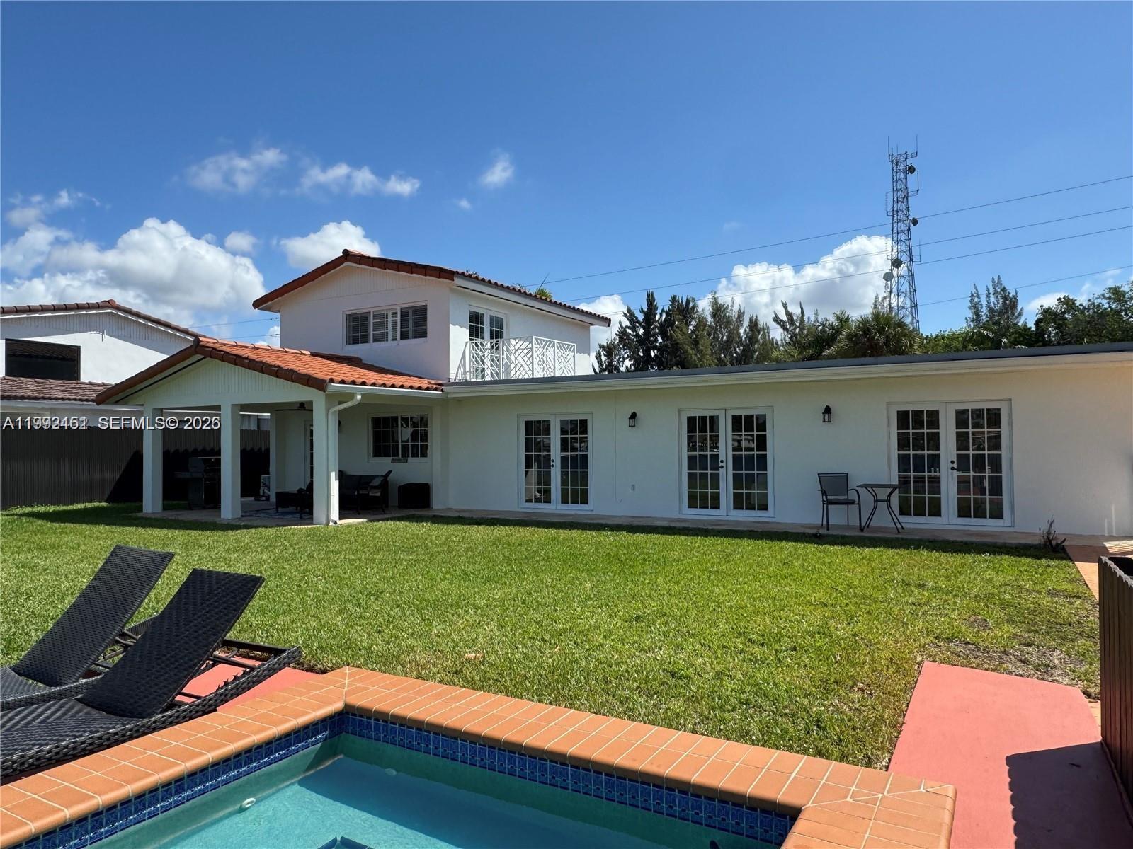 The exterior of a two-story house features a swimming pool, lawn, and multiple glass doors — 18400 NW 78th Ave, Hialeah FL 33015, HIALEAH, FL