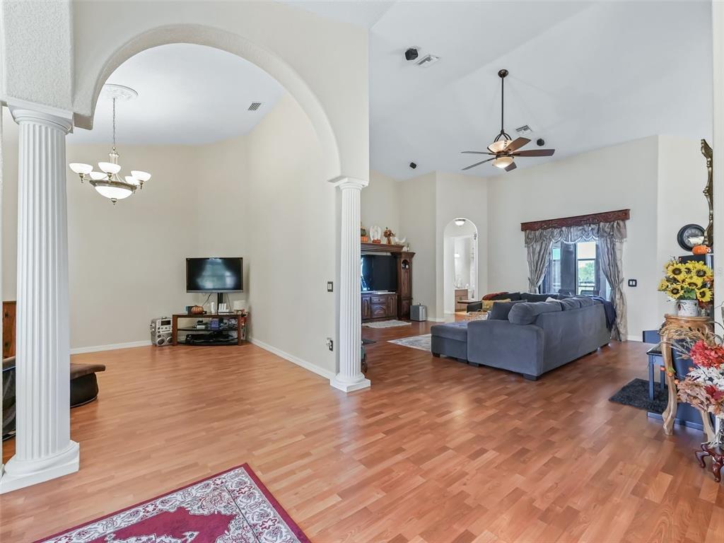 A living room features hardwood floors, an arched entryway with columns, and a ceiling fan — 9926 SE SUNSET HARBOR ROAD, SUMMERFIELD, FL
