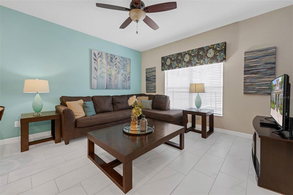 A living room features a brown sectional sofa, a coffee table, and light blue walls — 4805 BRIER ROSE LANE, KISSIMMEE, FL