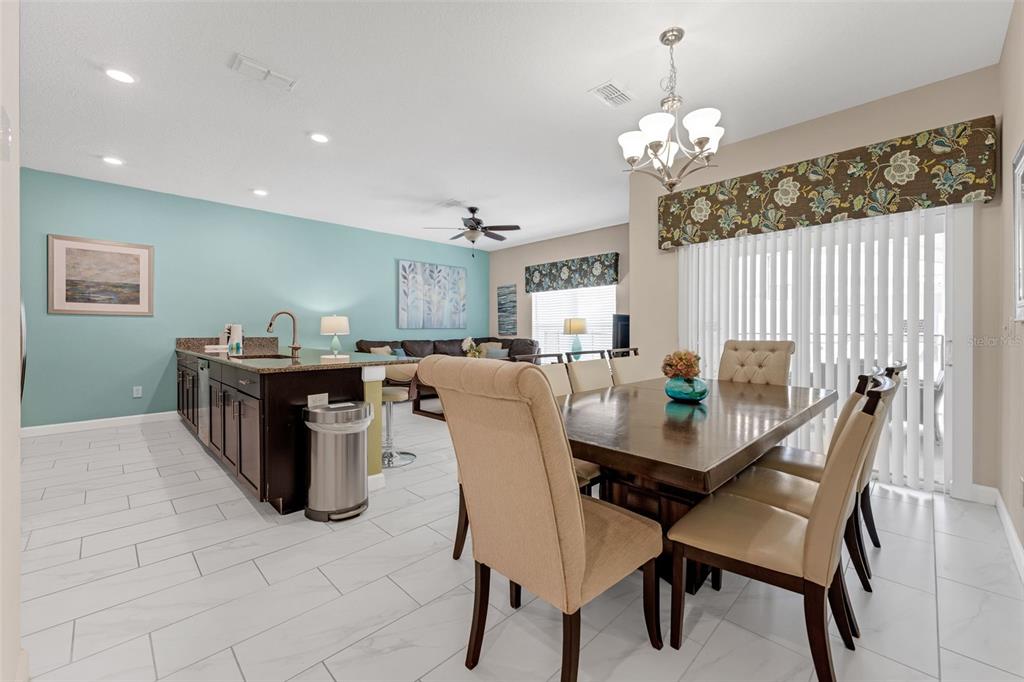 A dining area with a wooden table and chairs adjacent to a kitchen with island — 4805 BRIER ROSE LANE, KISSIMMEE, FL