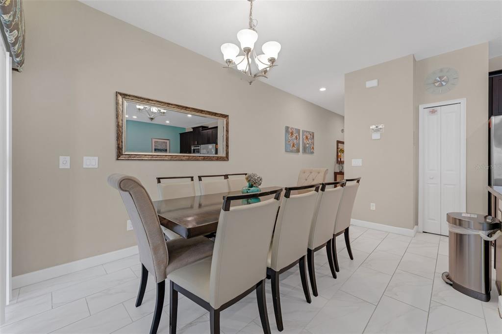 A dining room features a dark wood table, upholstered chairs, a chandelier, and tiled floors — 4805 BRIER ROSE LANE, KISSIMMEE, FL