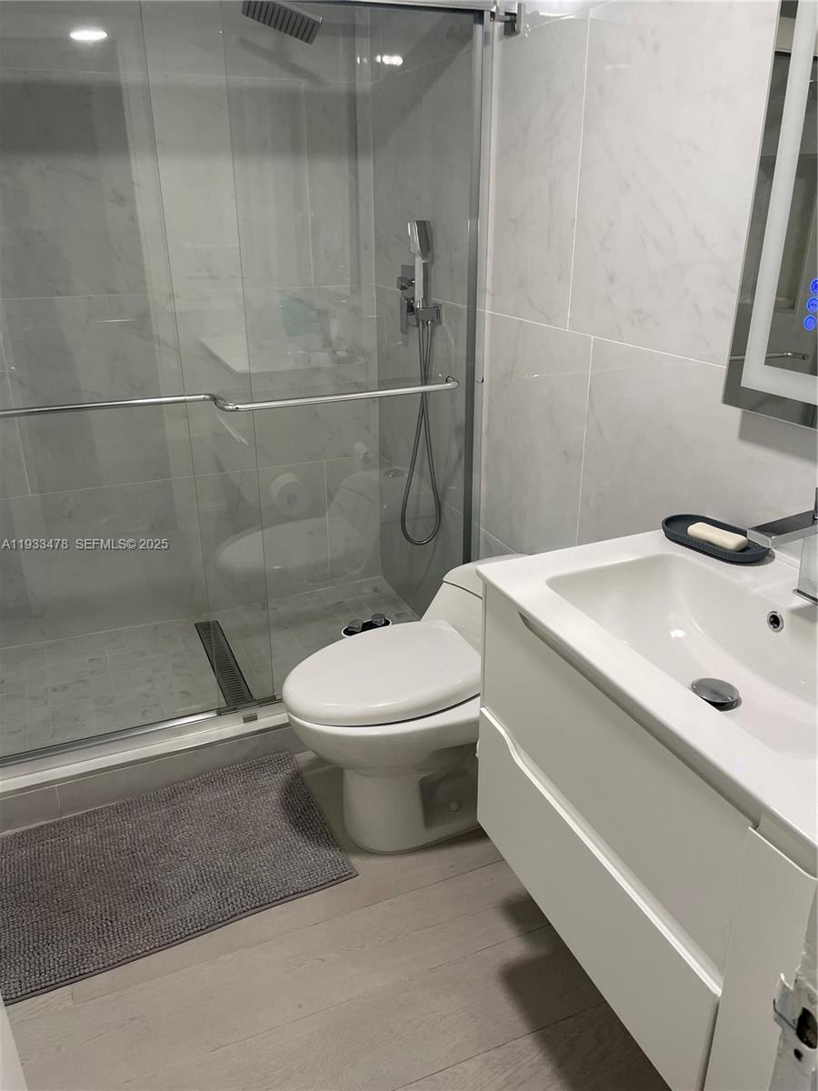 A modern bathroom features a glass-enclosed shower, a white vanity, and light-colored tile flooring — 2030 S Ocean Dr # 805, Hallandale Beach FL 33009, HALLANDALE BEACH, FL