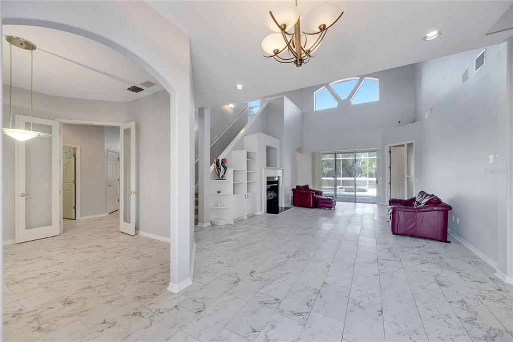 A spacious living room features white marble-look tile flooring, a fireplace, and a vaulted ceiling — 17904 CACHET ISLE DRIVE, TAMPA, FL