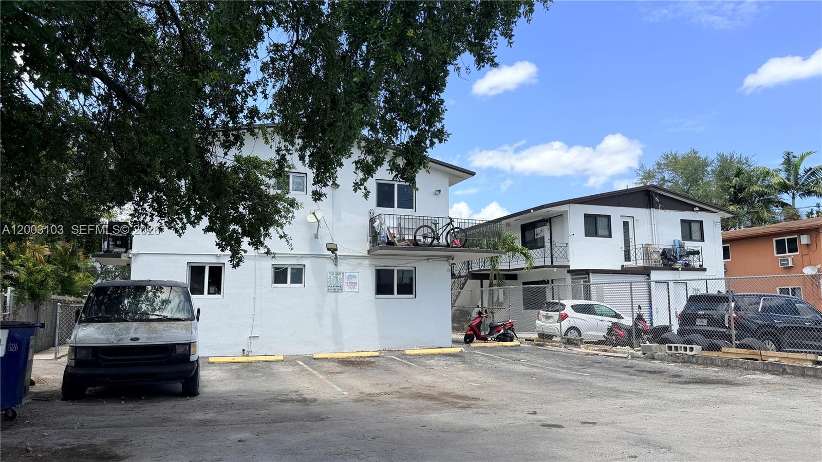 A two-story white apartment building with a parking lot and several vehicles in front — 33 NW 21st Ave, Miami FL 33125, MIAMI, FL
