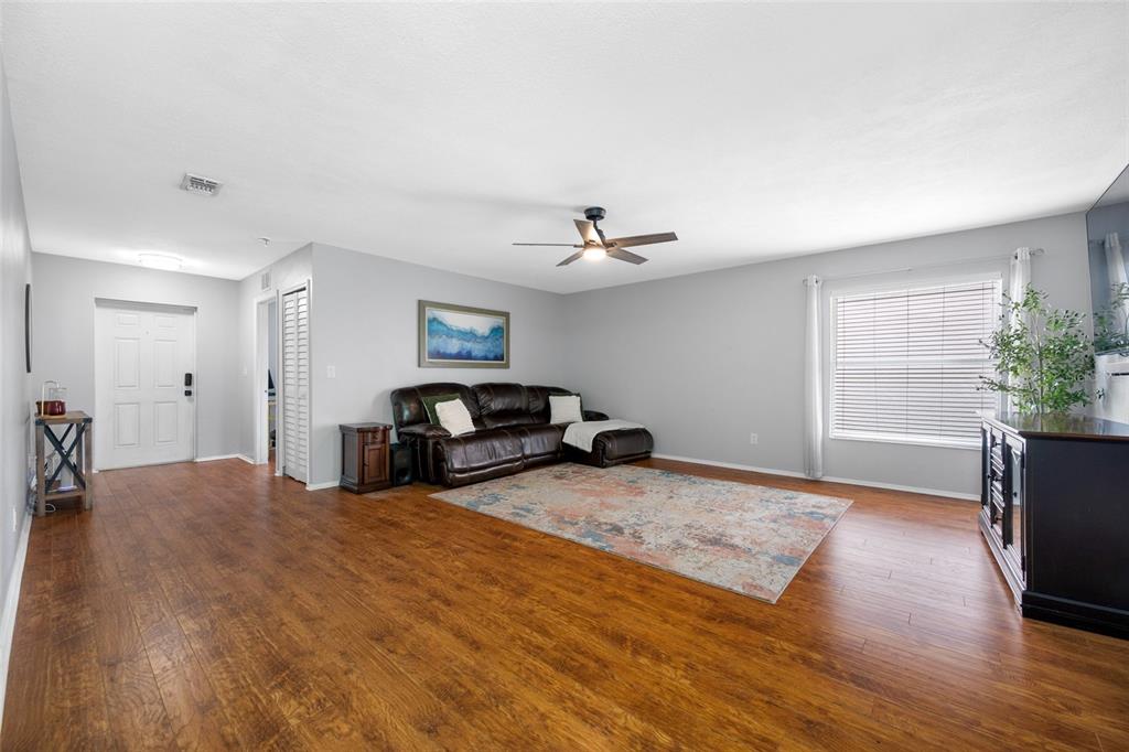 A living room with wood-look flooring, a brown leather sectional, and a ceiling fan — 13953 JACOBSON DRIVE, ODESSA, FL