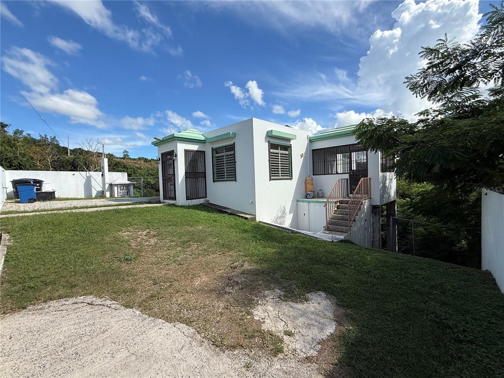 A white house with green trim and a grassy yard under a blue sky — Carr 411 km 0.20 BO. CALVACHE, RINCON, PR