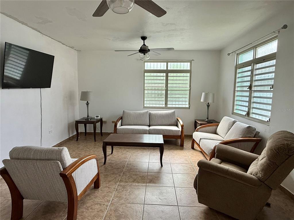 A living room features tile flooring, a ceiling fan, a sofa, and two armchairs — Carr 411 km 0.20 BO. CALVACHE, RINCON, PR