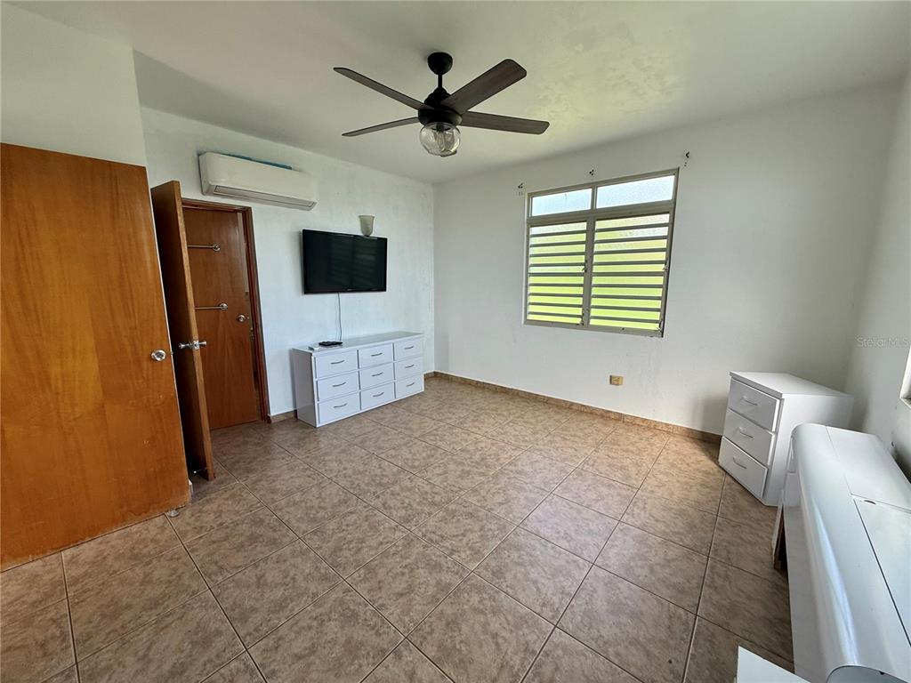 A bedroom features tile flooring, a ceiling fan, a wall-mounted television, and two white dressers — Carr 411 km 0.20 BO. CALVACHE, RINCON, PR