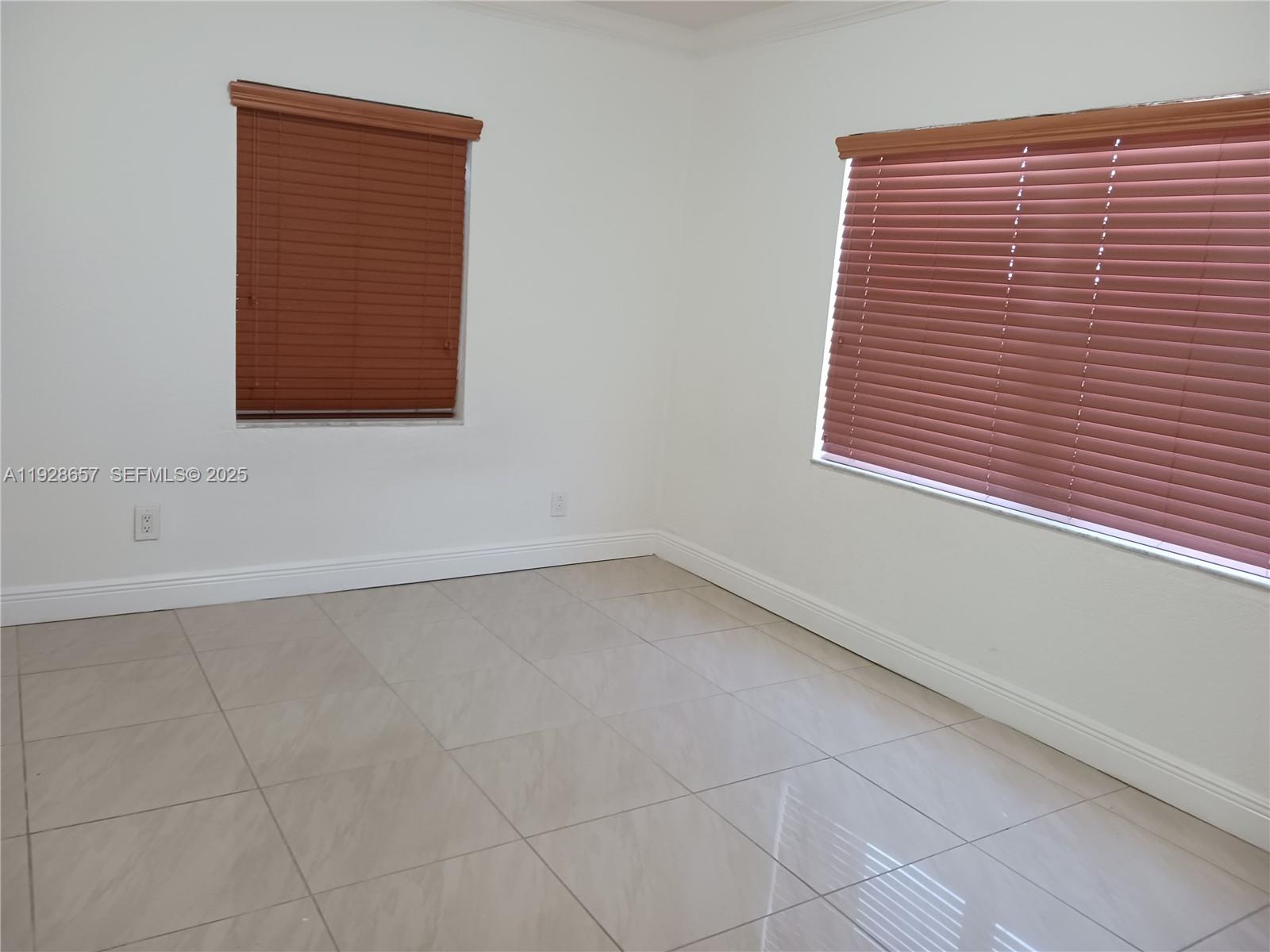 An empty room features white walls, light-colored tile flooring, and two windows with brown blinds — 650 SW 44th Ct, Miami FL 33134, MIAMI, FL