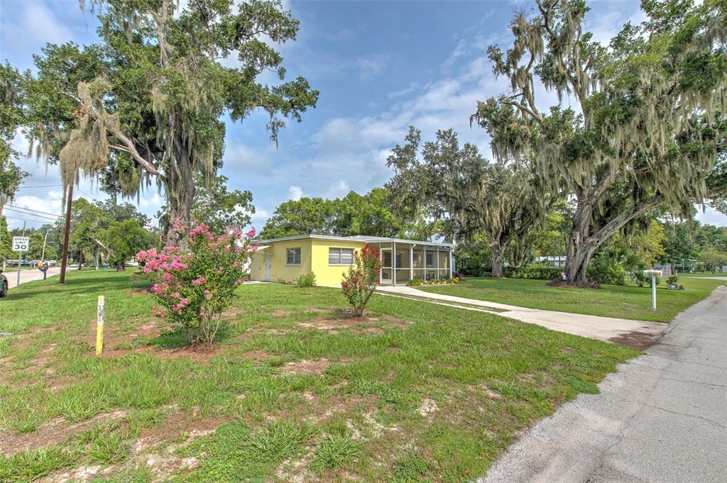 A yellow single-story house with a screened-in porch sits on a grassy lot with trees — 1675 N TATE AVENUE, BARTOW, FL