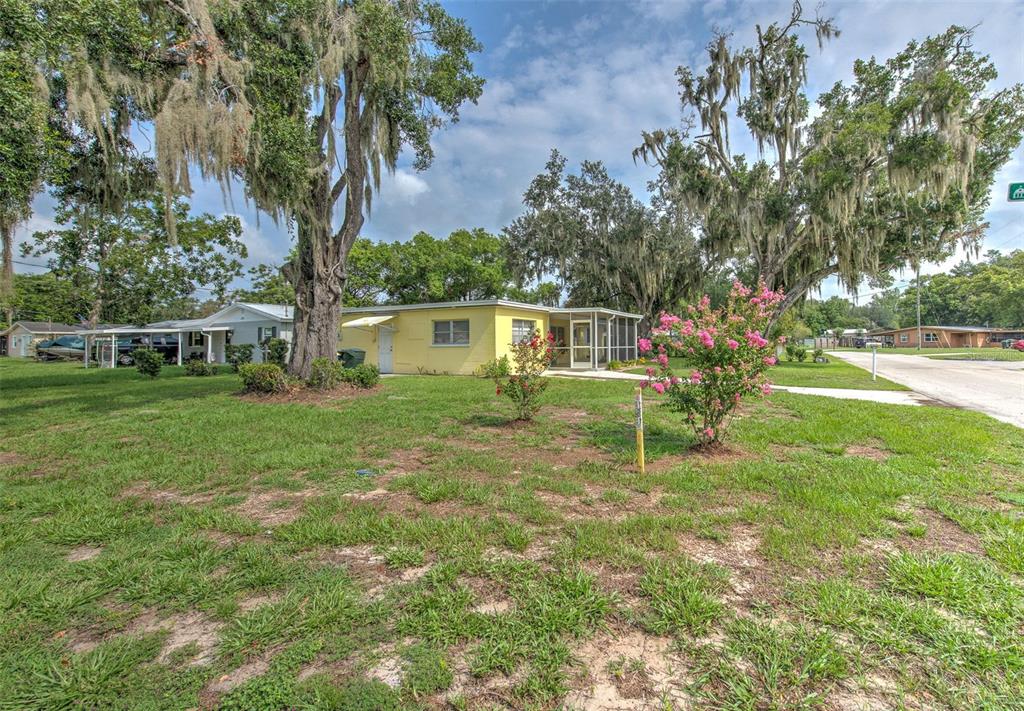 A yellow single-story house with a screened porch sits on a grassy lot with trees — 1675 N TATE AVENUE, BARTOW, FL