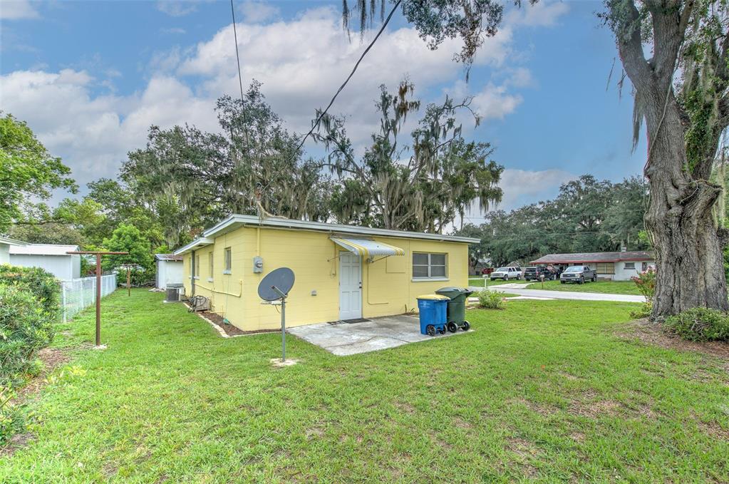 A yellow concrete block house features a small concrete patio and a satellite dish — 1675 N TATE AVENUE, BARTOW, FL