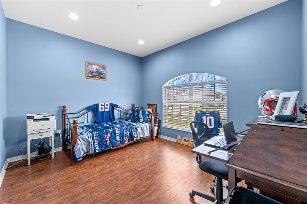 A backyard features a green lawn, a white vinyl fence, and a screened-in patio area — 6751 BOULDER RUN LOOP, WESLEY CHAPEL, FL