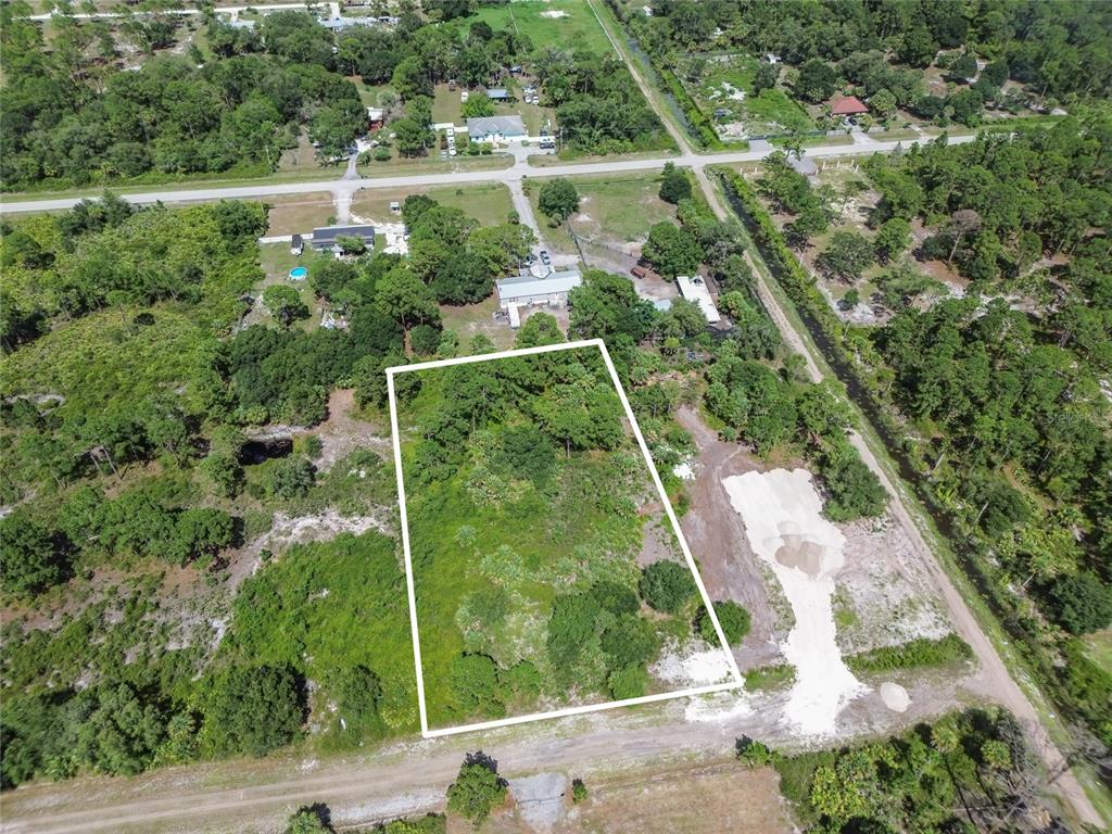 An aerial view shows a rectangular, wooded vacant lot outlined in white — 575 S PALOMINO STREET, CLEWISTON, FL
