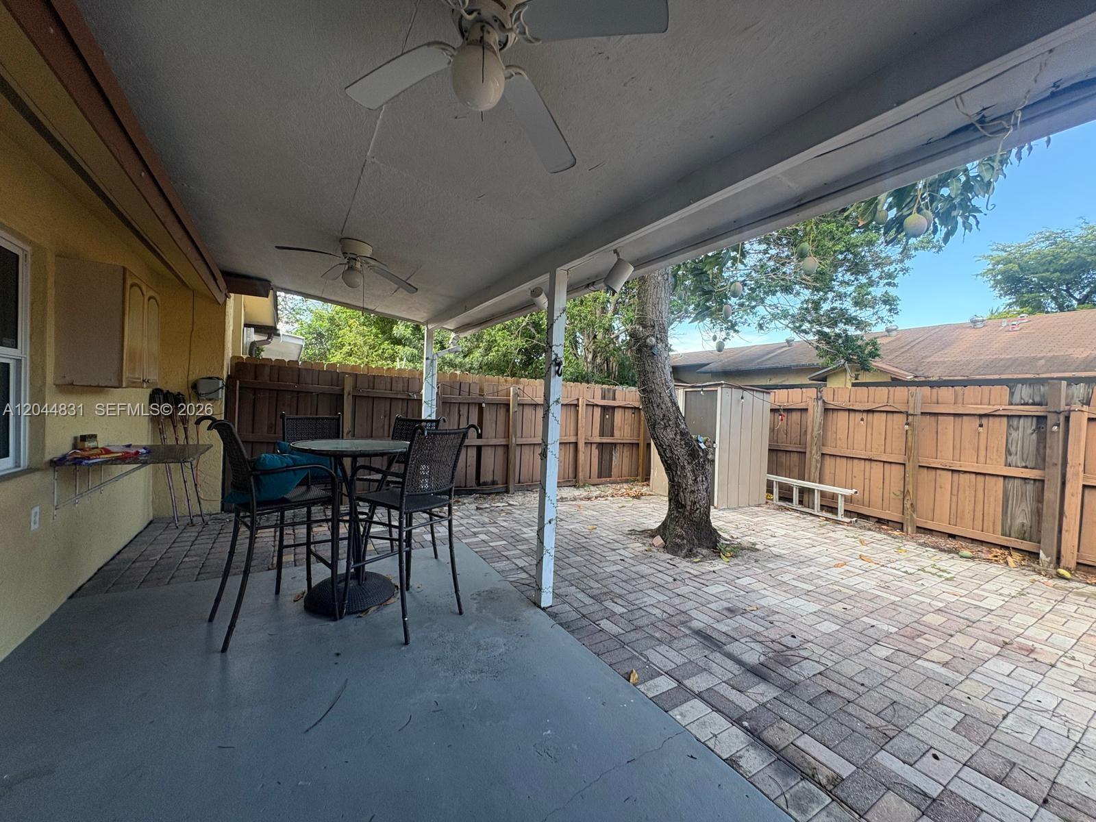 A covered patio features a paved floor, a dining set, and a tree in the yard — 4402 NW 5th Ave # 4402, Deerfield Beach FL 33064, DEERFIELD BEACH, FL