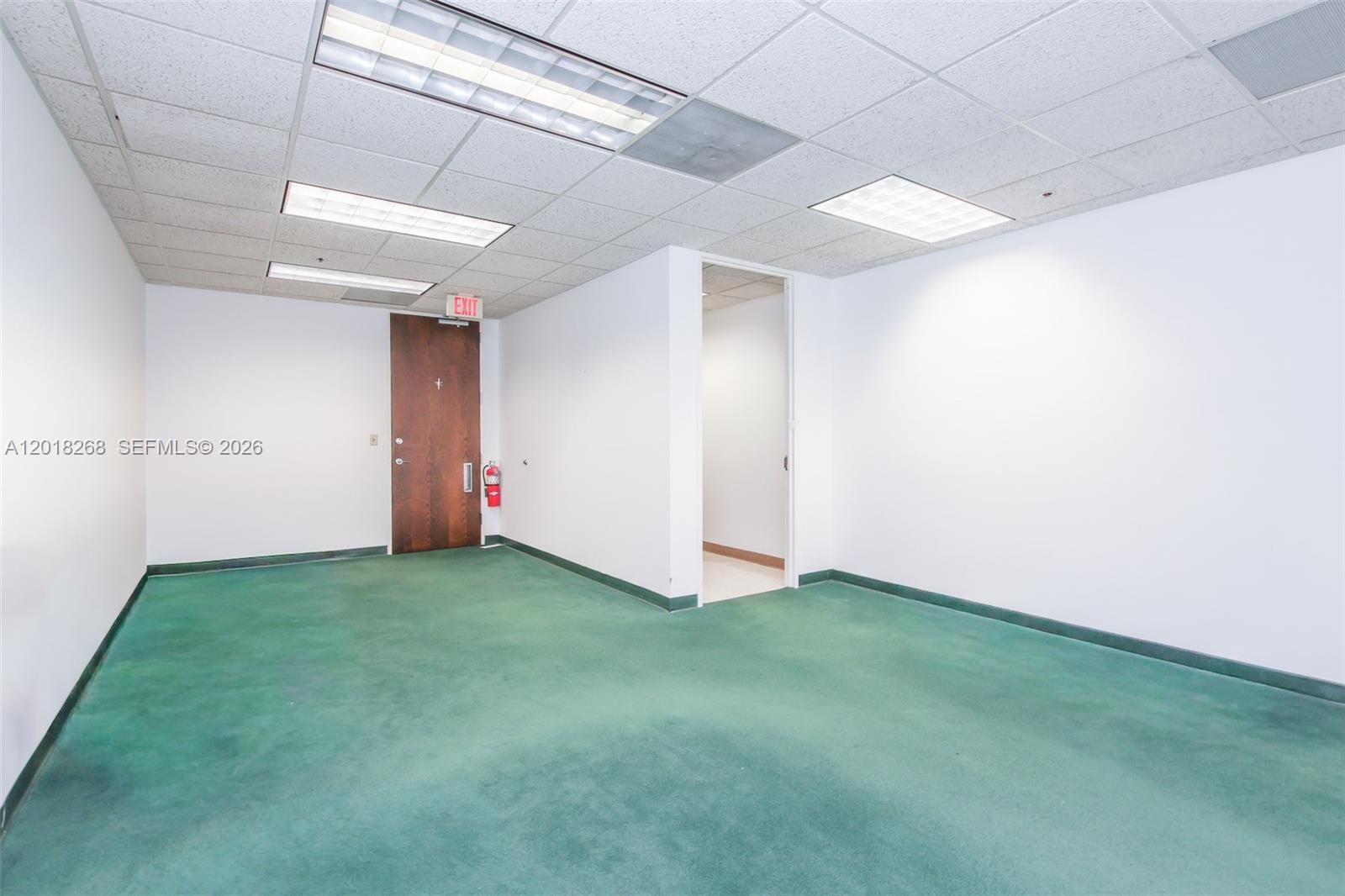An empty office space features white walls, a green carpeted floor, and a drop ceiling — 1900 Glades Rd # 353, Boca Raton FL 33431, BOCA RATON, FL