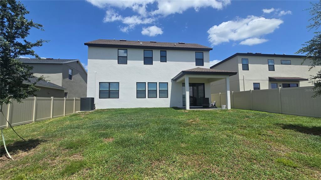 The back exterior of a two-story house features a covered patio and a fenced yard — 12163 STIRRUP DRIVE, DADE CITY, FL