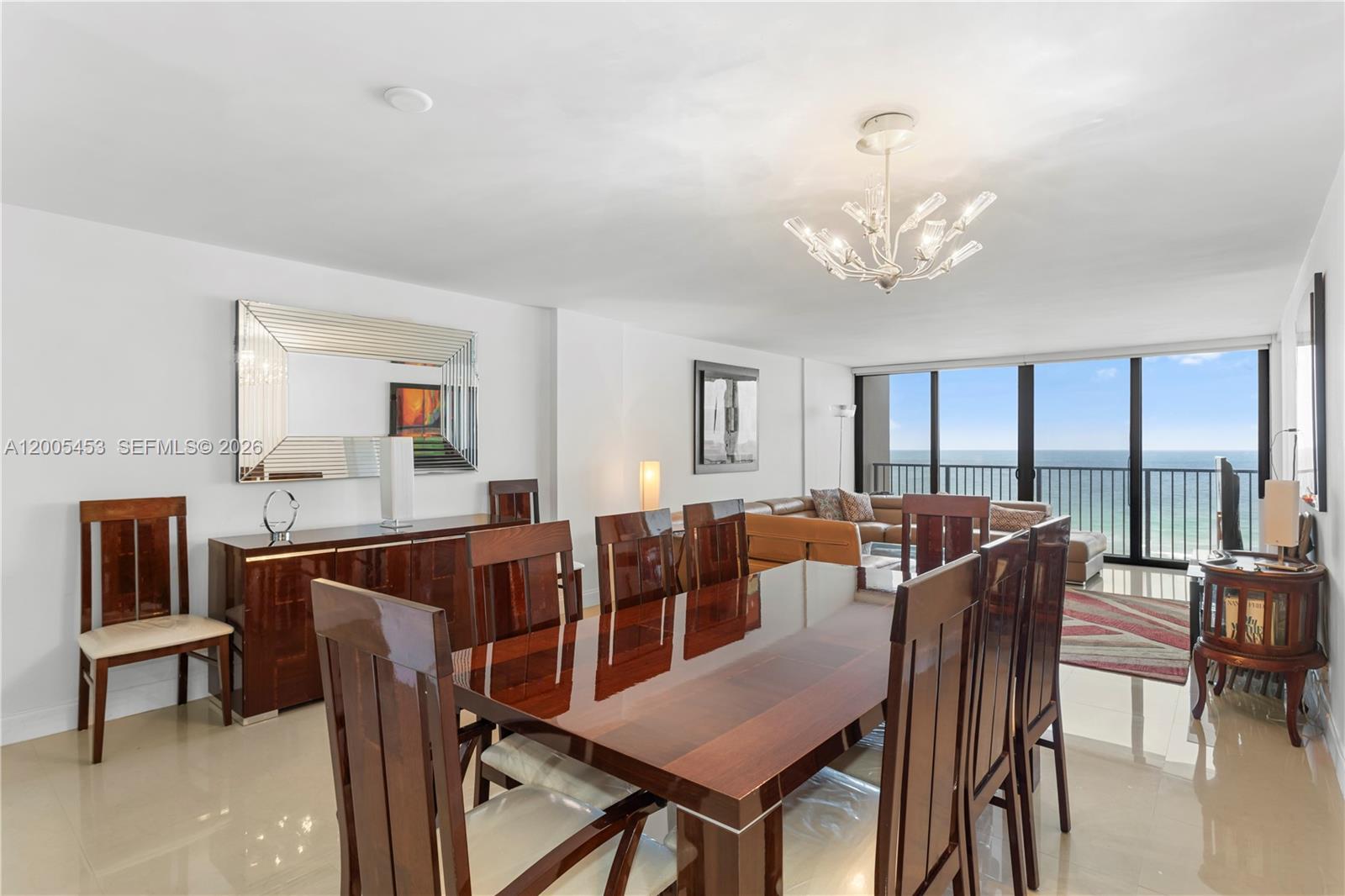A dining room with a wooden table and chairs overlooks the ocean through large windows — 2101 S Ocean # 1001, Hollywood FL 33019, HOLLYWOOD, FL