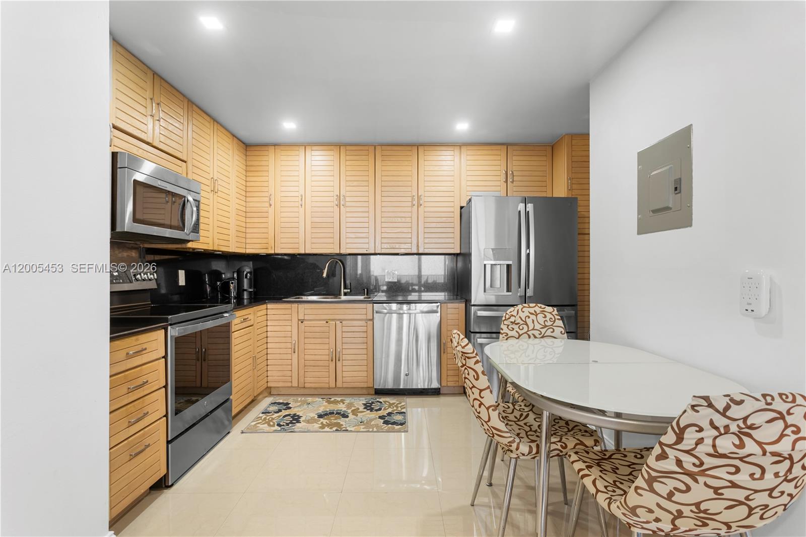 A kitchen features light wood slatted cabinets, stainless steel appliances, and a small dining table — 2101 S Ocean # 1001, Hollywood FL 33019, HOLLYWOOD, FL