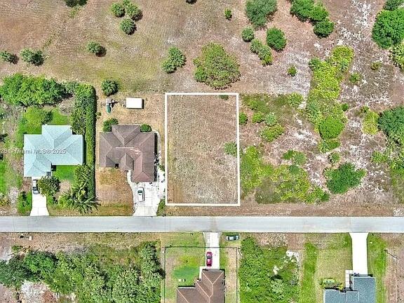 An aerial view shows a vacant rectangular lot situated between two houses on a street — 914 MERCURY AVENUE S, LEHIGH ACRES, FL