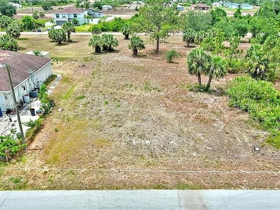 An aerial view shows a vacant, grassy residential lot next to a house — 914 MERCURY AVENUE S, LEHIGH ACRES, FL