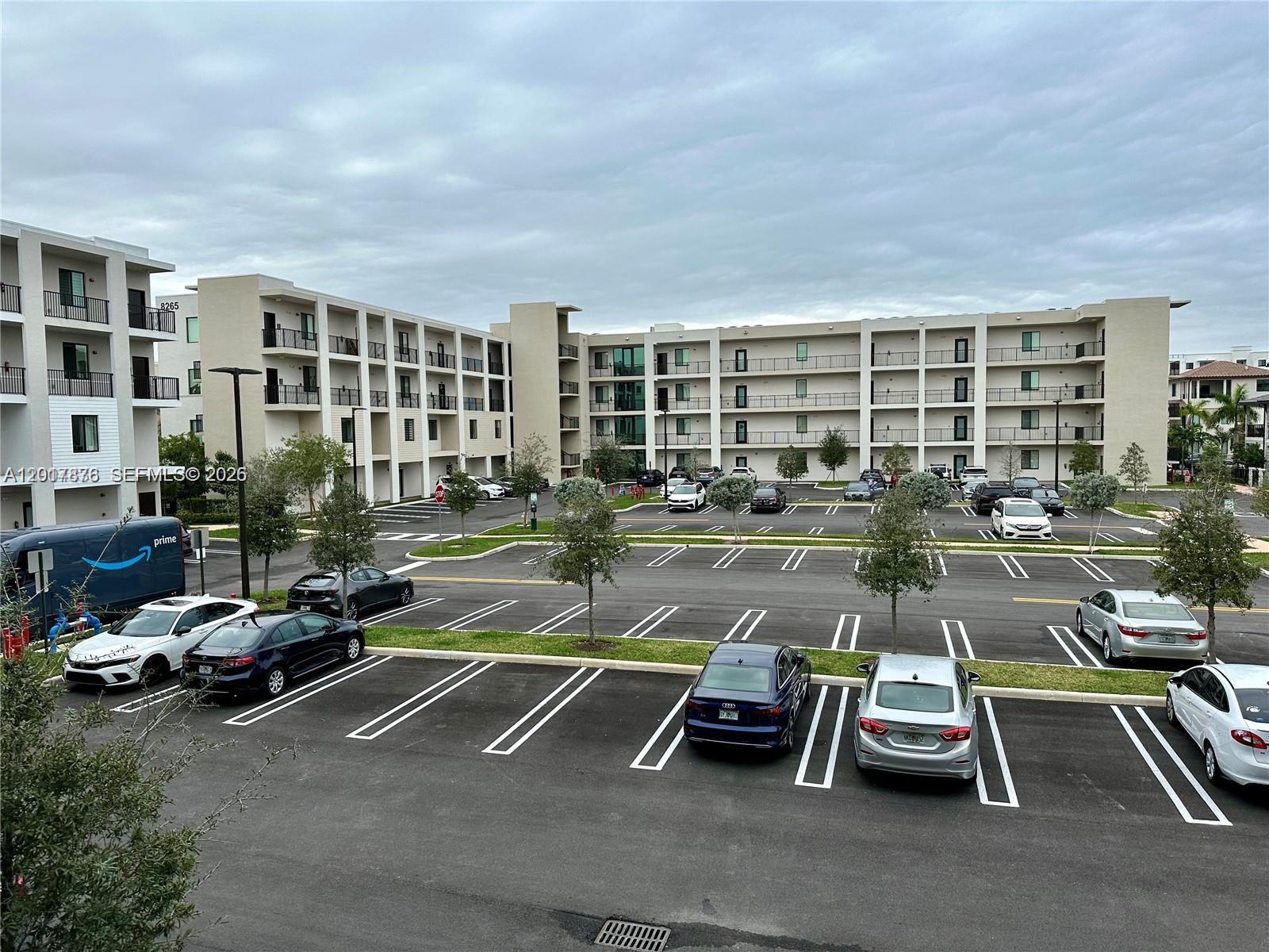 An exterior view of a multi-story apartment building with a large parking lot in front — 8201 NW 41st St # 203, Doral FL 33166, DORAL, FL