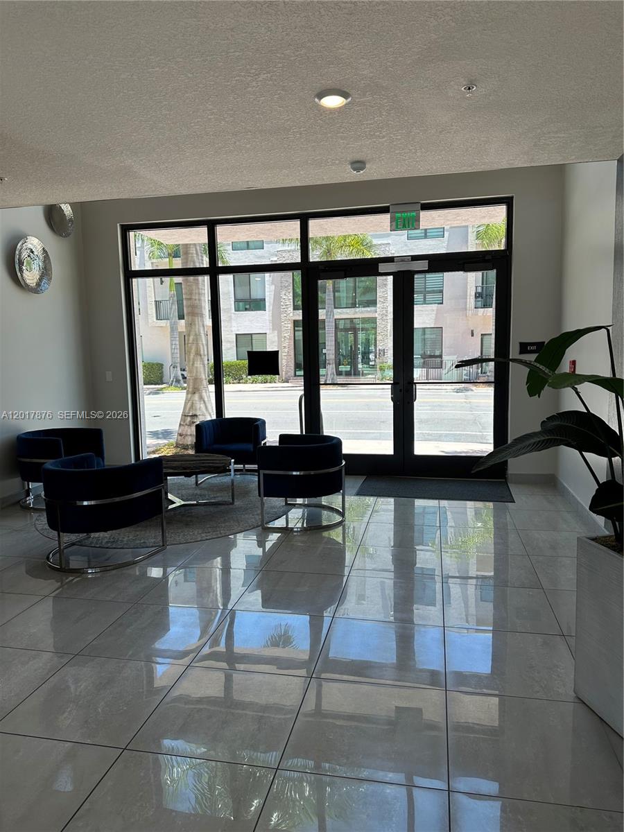 A modern lobby features tiled floors, dark blue armchairs, and glass doors leading outside — 8201 NW 41st St # 203, Doral FL 33166, DORAL, FL