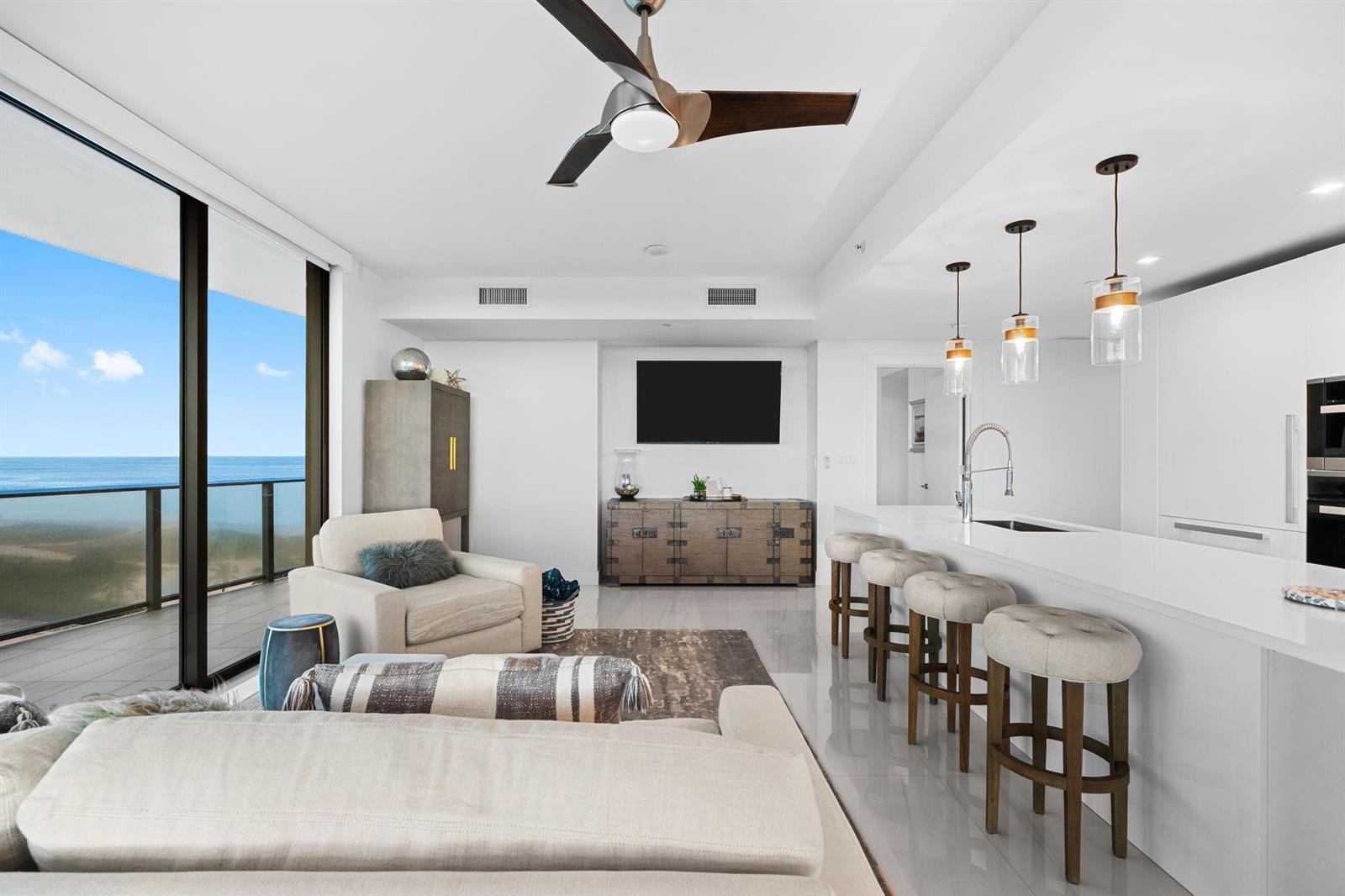 A modern open-concept living room and kitchen area features a balcony with ocean views — 730 N Ocean Boulevard # 701, Pompano Beach FL 33062, POMPANO BEACH, FL