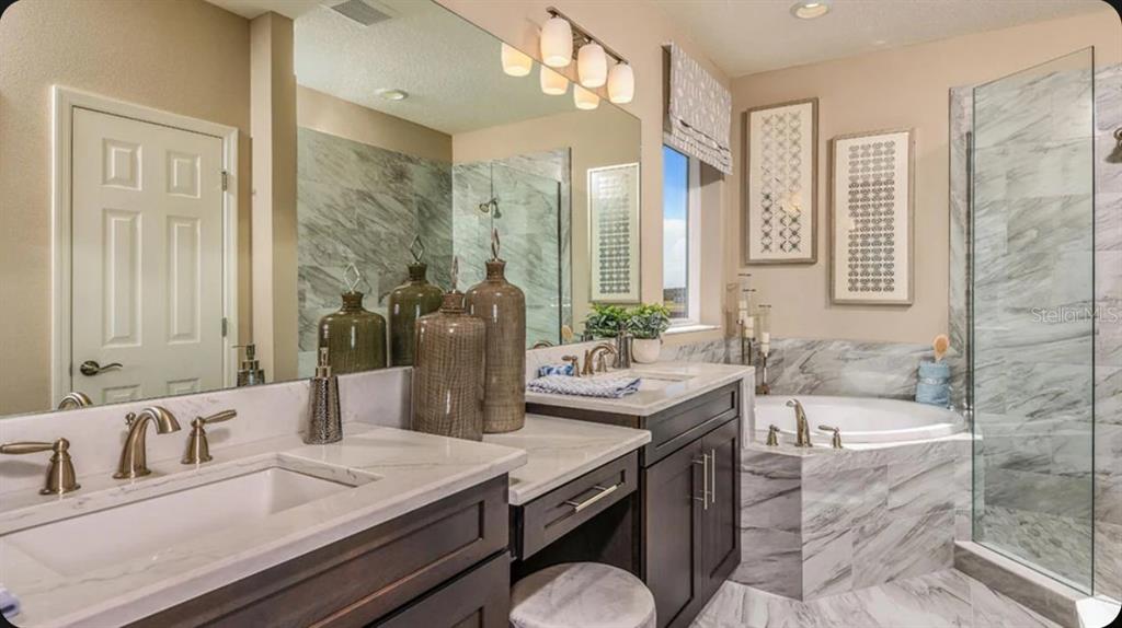 A bathroom features dark wood cabinets, marble countertops, a soaking tub, and a glass shower — 35709 EMBERVIEW DRIVE, ZEPHYRHILLS, FL