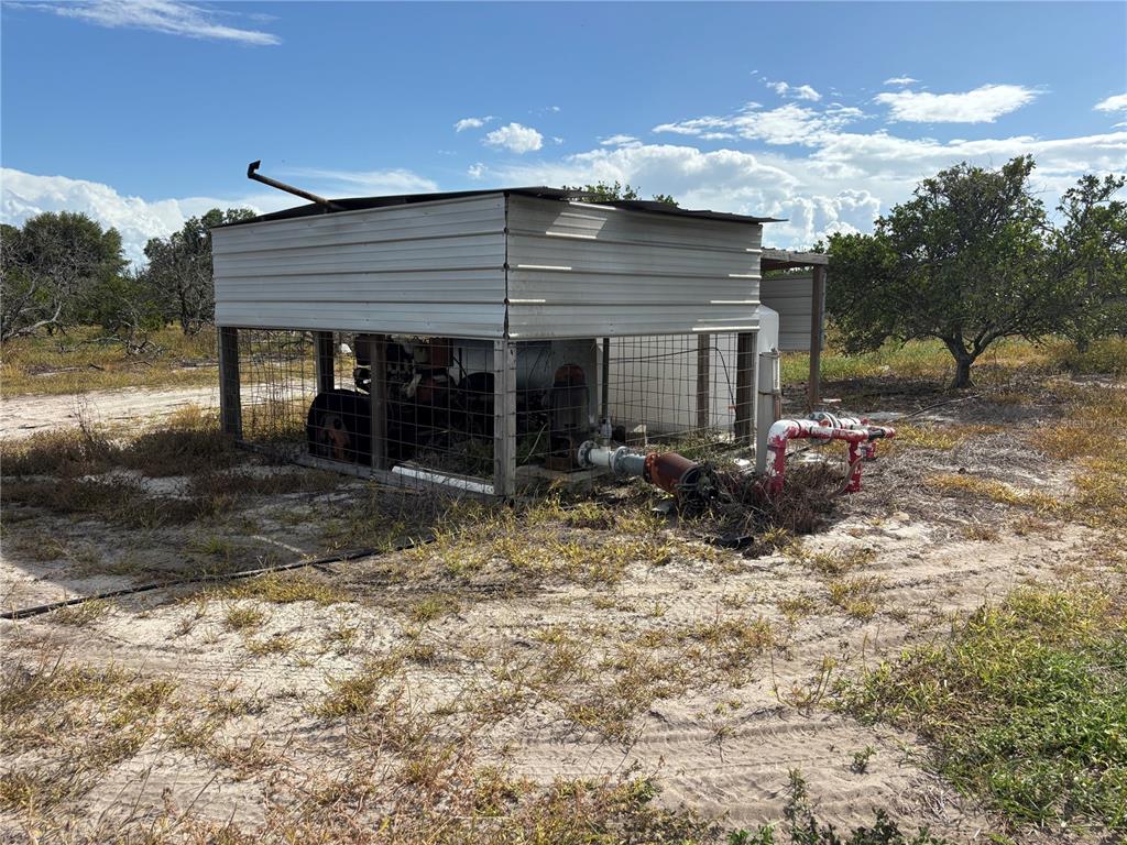 An outdoor metal pump house structure sits on a sandy lot with exposed piping — LAKE BUFFUM ROAD W, FORT MEADE, FL