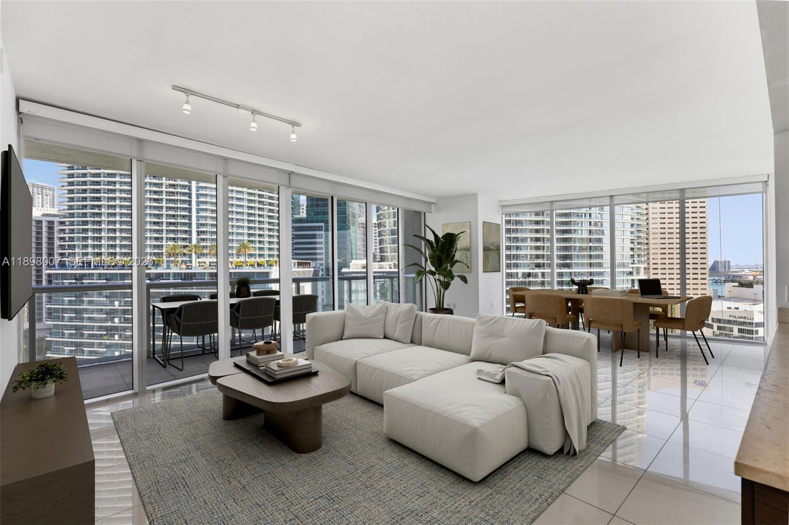 A modern living room with a white sectional sofa, tile floors, and floor-to-ceiling city views — 465 Brickell Ave # 1602, Miami FL 33131, MIAMI, FL