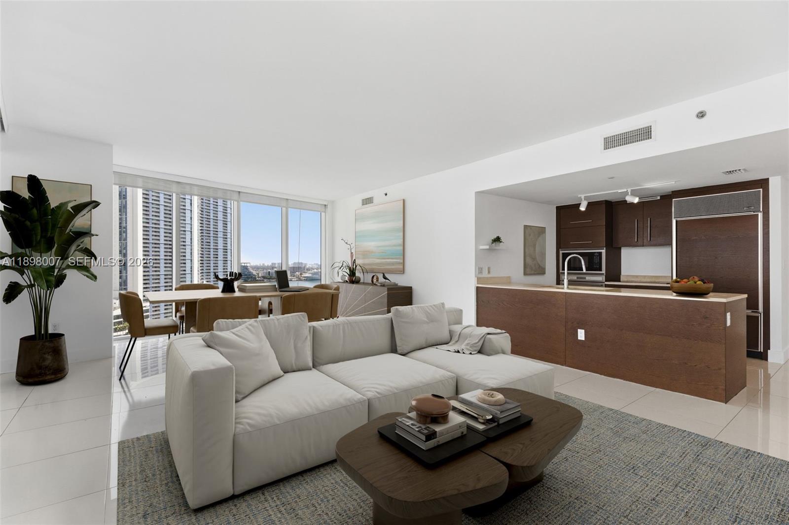 A modern living room and kitchen area features a white sofa, dining set, and city views — 465 Brickell Ave # 1602, Miami FL 33131, MIAMI, FL