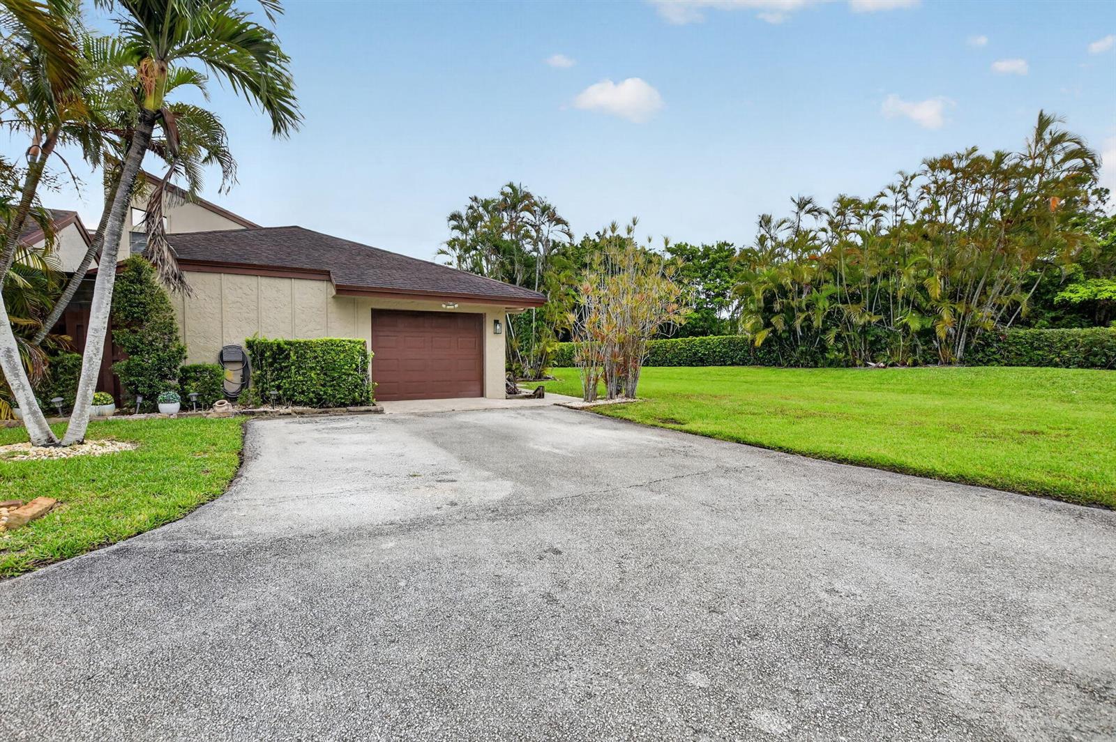 A tan house with a brown garage door and a paved driveway sits on grass — 22718 Vistawood Way, Boca Raton FL 33428, BOCA RATON, FL